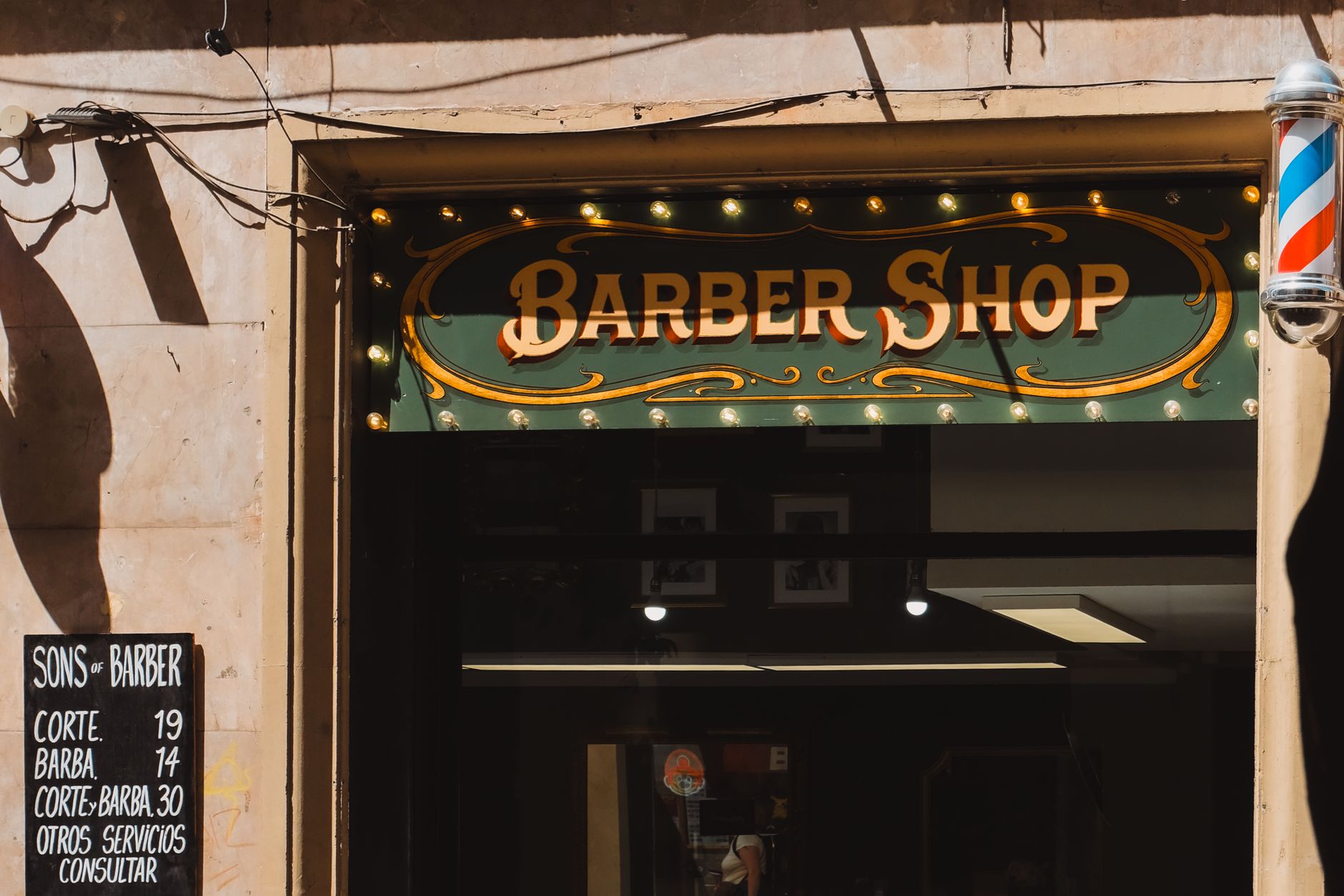 A vintage-style barber shop entrance in Barcelona, featuring classic signage and decor.